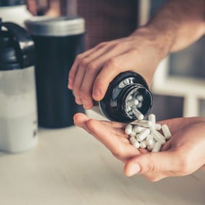 Cropped image of handsome young sportsman preparing sport nutrition in kitchen at home